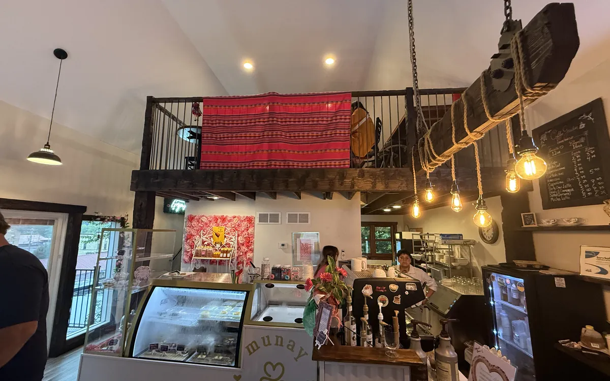 Inside Munay on opening day: the pastry case, the coffee bar, and the loft with an Andean textile on the railing.